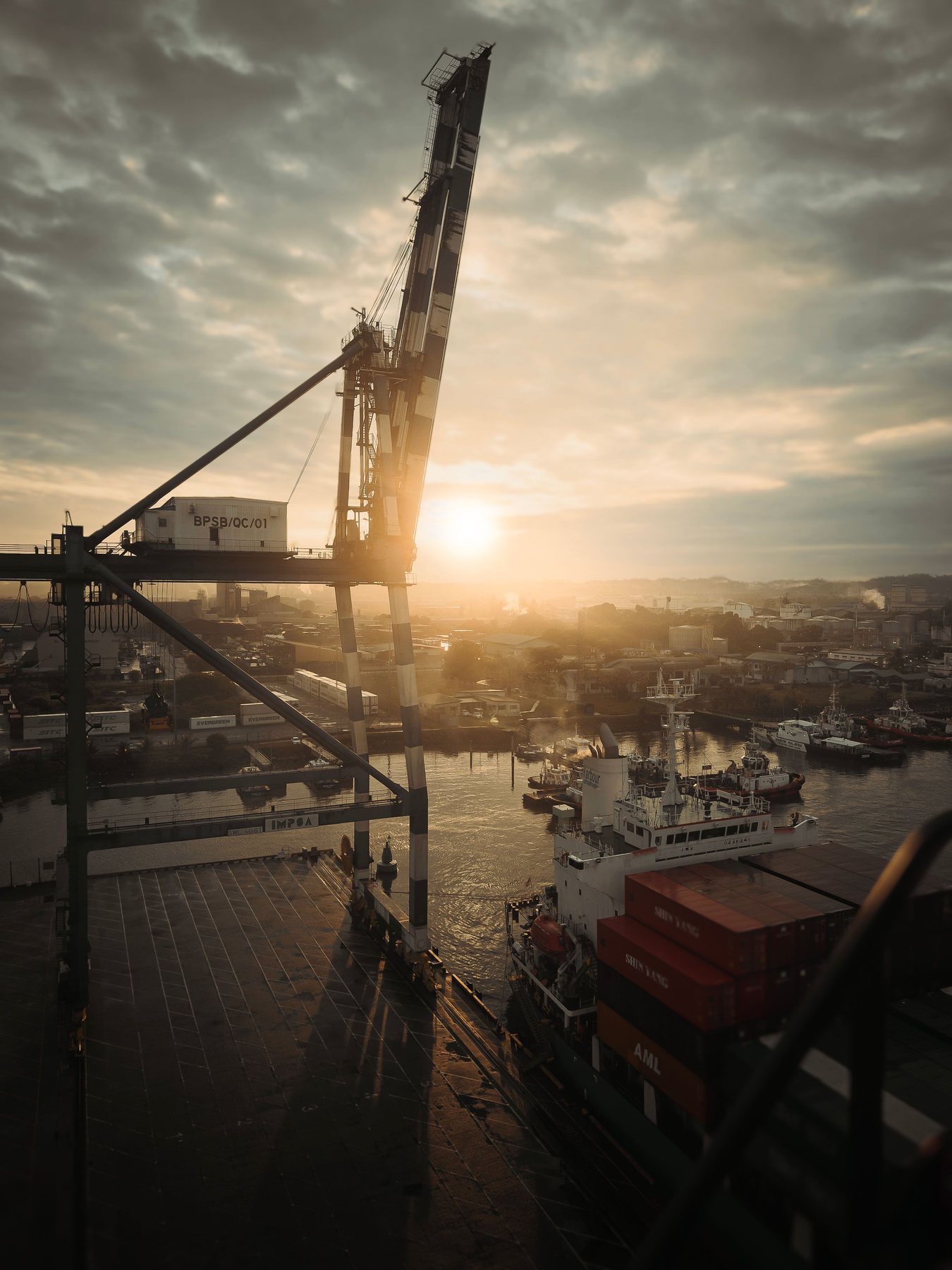 Container cranes and cargo ships at a working port at sunrise
